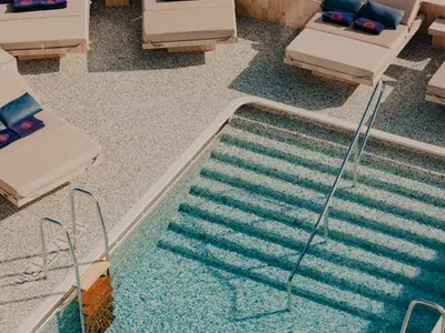 Blick von oben auf den geschmackvoll gestalteten Poolbereich mit Pooltreppe und Liegestühlen an Bord der Explora II.