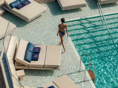 Blick von oben auf eine Frau im blauen Bikini, die im flachen Poolbereich auf dem Deck der Explora II geht.