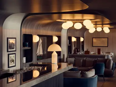 Elegante Bar-Lounge an Bord der Explora II mit geschwungener Holzdecke, Kugel-Lampen und gemütlichen Sesseln.