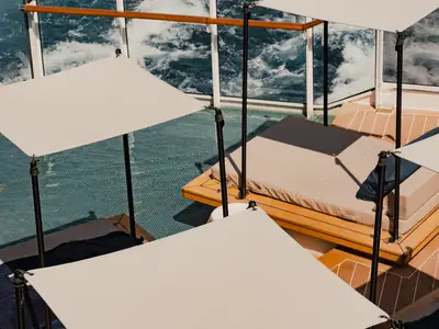 Luxuriöse Sonnenliegen mit hellen Sonnensegeln auf dem Holzdeck mit Blick aufs Meer an Bord der Explora II.