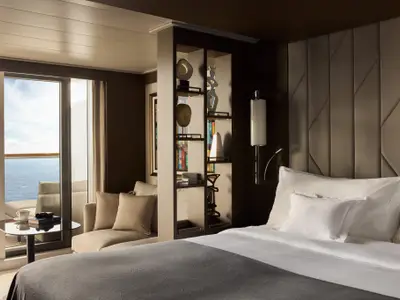 Elegantes Schlafzimmer einer Suite an Bord der Explora II mit Blick auf das Meer und stilvollem Raumteiler.