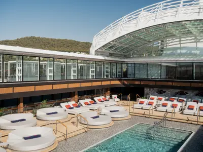 Überdachter Poolbereich mit stilvollen Sonnenliegen, Daybeds und Glasüberdachung an Bord der Explora III.