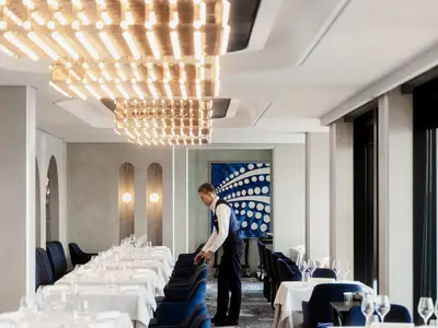 Ein Kellner richtet Stühle im elegant eingerichteten Restaurant Anthology an Bord der Explora III her.
