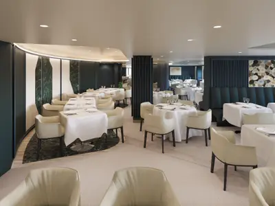 Blick in das luxuriöse Restaurant Fil Rouge an Bord der Explora III mit weiß gedeckten Tischen.