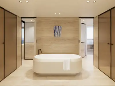 Freistehende Badewanne vor einer beigen Steinwand im luxuriösen Badezimmer der Owner's Residence an Bord der Explora III.