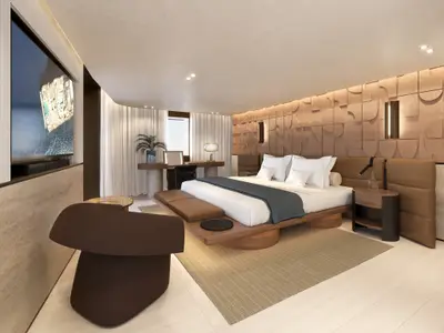 Elegantes Schlafzimmer in einer Suite an Bord der Explora III mit hölzernem Bettrahmen, Sessel und Fernseher.
