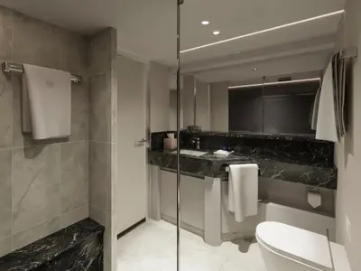 Modernes Badezimmer mit schwarzem Marmor, Spiegelfront und Handtüchern im Premier Penthouse der Explora III.