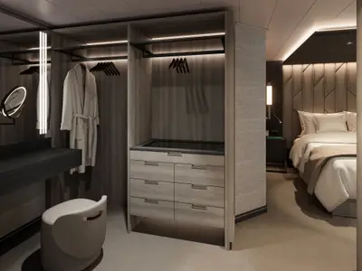 Geräumiger begehbarer Kleiderschrank mit Kommode und Bademantel sowie Schlafbereich in einer Suite an Bord der Explora III.
