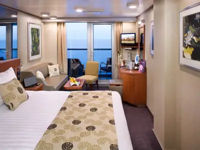Blick in eine gemütliche Balkonkabine an Bord der Eurodam mit Bett, Sofa, Sessel und Balkon zum Meer.