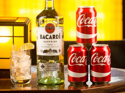 Eine Flasche Bacardi Superior Rum, drei Dosen Coca-Cola und ein Eisglas mit Limette an Bord der Eurodam.