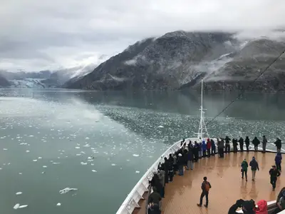 Gäste an Bord der Eurodam blicken vom Bug des Schiffes auf eine eisige Bucht mit Gletschern und Bergen in Alaska.
