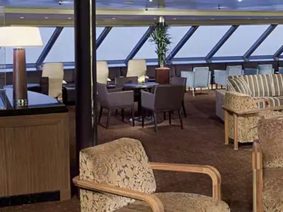 Elegante Lounge an Bord der Eurodam mit gemütlichen Sesseln, Holzelementen und großen Panoramafenstern.