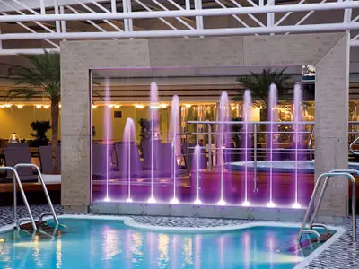 Der Lido Pool an Bord der Eurodam bei Nacht mit stimmungsvoll beleuchteten Wasserspielen in Violett.