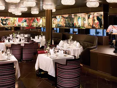 Elegant eingedeckte Tische und gestreifte Sessel im Pinnacle Grill Restaurant an Bord der Eurodam.