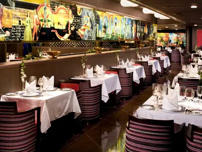 Elegante Tischgedecke im Restaurant Pinnacle Grill an Bord der Eurodam mit kunstvollem Wandgemälde.