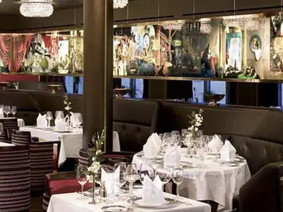 Elegantes Restaurant an Bord der Eurodam mit weiß gedeckten Tischen, Polstersesseln und historischen Gemälden an der Wand.