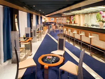 Die stilvolle Pinnacle Bar an Bord der Eurodam mit einer langen Bar, Holzhockern und modernen Sitzecken auf blauem Teppich.