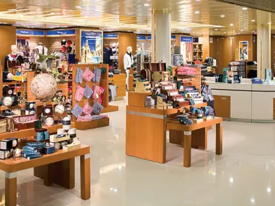 Ein heller Souvenir- und Geschenkshop an Bord der Eurodam mit hölzernen Ausstellungsflächen, Globen, Kleidung und maritimen Dekoartikeln.