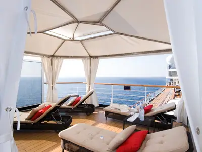 Blick aus einer privaten Cabana im Retreat-Bereich an Bord der Eurodam mit Sonnenliegen auf das blaue Meer.