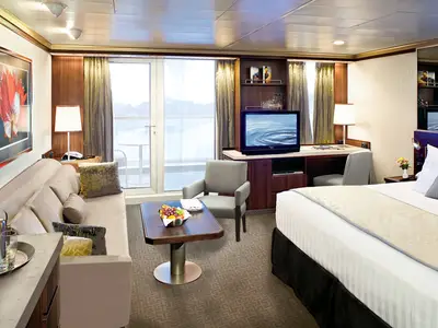 Blick in eine Signature Suite an Bord der Eurodam mit Doppelbett, Sofa, Couchtisch und Blick auf den Balkon.