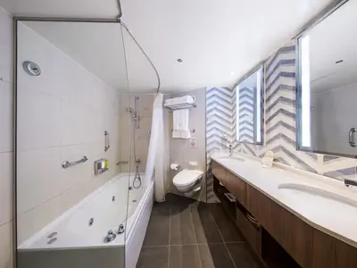 Das helle und geräumige Badezimmer einer Neptune Suite an Bord der Eurodam mit Badewanne, Toilette und Doppelwaschbecken.