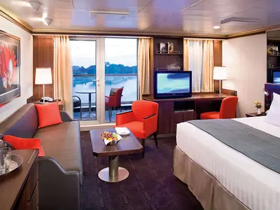 Blick in eine luxuriöse Signature Suite an Bord der Eurodam mit Doppelbett, Sitzecke und Balkon mit Aussicht.