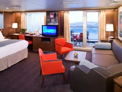 Ein Blick in die geräumige und elegant eingerichtete Neptune Suite an Bord der Eurodam mit großem Bett, Sitzecke und Balkon.