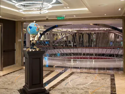 Eine glitzernde Weltkugel-Skulptur auf einer Stele im modern gestalteten Atrium an Bord der Koningsdam.