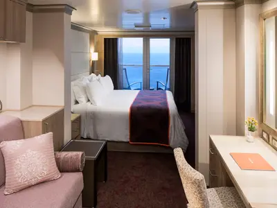 Eine helle, moderne Balkonkabine an Bord der Koningsdam mit großem Doppelbett, Sitzecke und Balkon mit Meerblick.