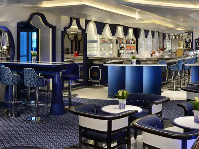 Das in Blau und Weiß gestaltete Grand Dutch Cafe an Bord der Koningsdam mit gemütlichen Sitzecken und einer Bar.