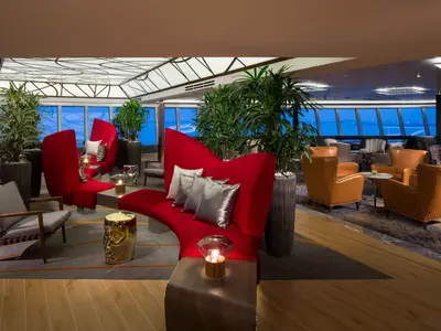 Die elegante Crow's Nest Lounge an Bord der Koningsdam mit roten Designersitzmöbeln, Ledersesseln und Ausblick auf das Meer.