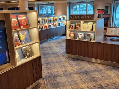 Blick in die helle, modern eingerichtete Bibliothek an Bord der Koningsdam mit Buchregalen und gemütlicher Atmosphäre.