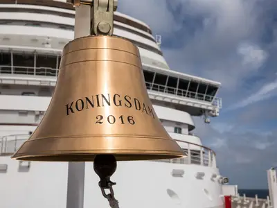 Nahaufnahme der messingfarbenen Schiffsglocke mit der Gravur Koningsdam 2016 an Bord des Kreuzfahrtschiffes.