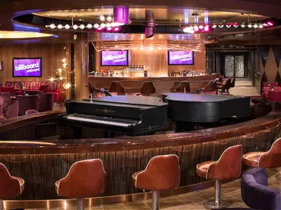 Die stilvolle Musik-Lounge Billboard Onboard an Bord der Koningsdam mit zwei Klavieren und einer edel beleuchteten Bar.