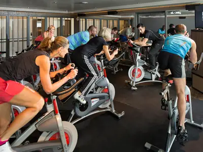 Mehrere Personen trainieren beim Spinning-Kurs auf Standfahrrädern im Fitness-Center an Bord der Koningsdam.