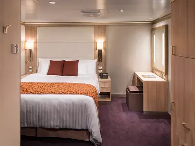 Eine modern eingerichtete Innenkabine an Bord der Koningsdam mit einem Doppelbett, orangefarbenen Akzenten und einem Frisiertisch.