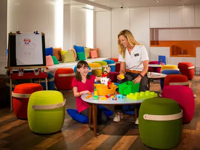 Ein Mädchen und eine Betreuerin spielen mit bunten Bausteinen im Club HAL an Bord der Koningsdam.