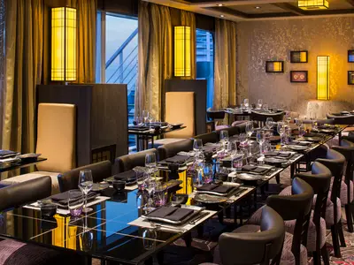 Elegant gedeckte Tische im asiatischen Restaurant Tamarind an Bord der Koningsdam mit warmer, stimmungsvoller Beleuchtung.