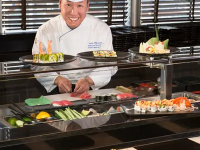 Ein Meisterkoch bereitet kunstvoll frisches Sushi an der Sushibar im Restaurant Tamarind an Bord der Koningsdam zu.