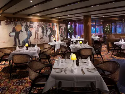 Elegantes Restaurant Rudi's Sel de Mer an Bord der Koningsdam mit fein eingedeckten Tischen, Wandgemälde und warmem Licht.