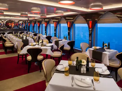 Blick in das stilvoll eingerichtete Canaletto Restaurant an Bord der Koningsdam mit gedeckten Tischen und herrlicher Aussicht auf das Meer.