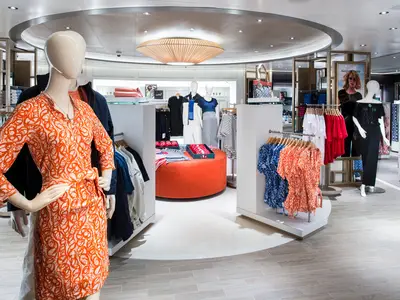 Ein Blick in eine Boutique an Bord der Koningsdam mit bunten Sommerkleidern, Schaufensterpuppen und einer modernen Einrichtung.