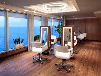 Moderner Friseursalon an Bord der Koningsdam mit weißen Sesseln, großen Spiegeln und Panoramafenstern mit Blick aufs Meer.