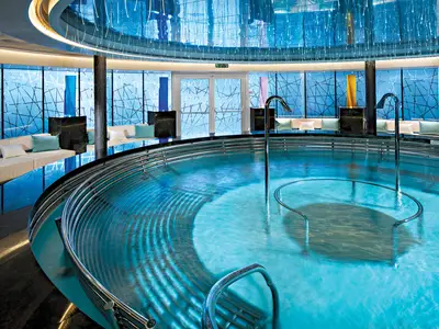 Der große, kreisrunde Hydrotherapie-Pool im Spa-Bereich an Bord der Koningsdam mit stimmungsvollem blauen Licht.