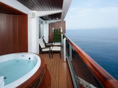 Luxuriöser Suite-Balkon an Bord der Koningsdam mit Whirlpool, Liegestühlen und Meerblick bei Tageslicht.