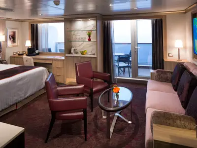 Eine geräumige, elegant eingerichtete Suite mit Sitzbereich, Balkon und Meerblick an Bord der Koningsdam.
