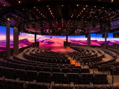 Das leere Theater 'World Stage' an Bord der Koningsdam mit halbrunden Sitzreihen und einer riesigen LED-Wand, die eine Wüstenlandschaft zeigt.