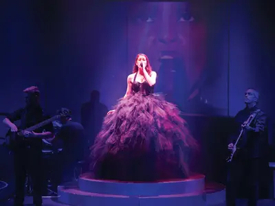 Eine Sängerin in einem ausladenden schwarzen Kleid singt auf der Bühne an Bord der Koningsdam, begleitet von einer Live-Band.