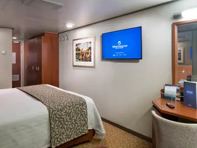 Blick in eine Außenkabine an Bord der Nieuw Amsterdam mit Doppelbett, Flachbildfernseher und Schreibtisch.