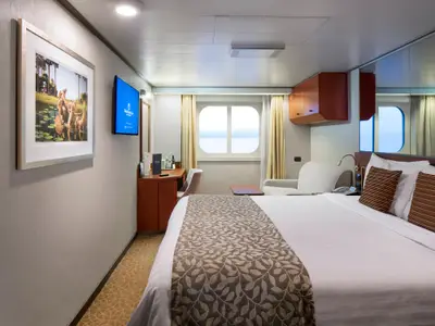 Eine geräumige Außenkabine an Bord der Nieuw Amsterdam mit Doppelbett, Sitzecke, Schreibtisch und großem Fenster zum Meer.